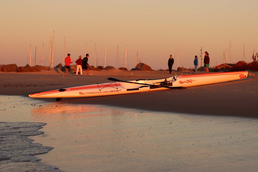 Surfski der ligger på en strand i aftensol
