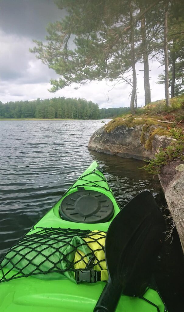 Grøn kajak i læ ved en svensk klippebred