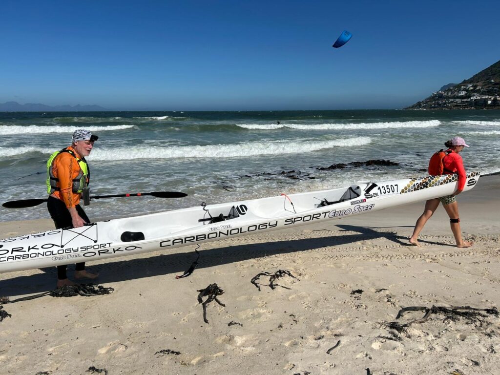 Surfski der bæres ved vandet på kysten