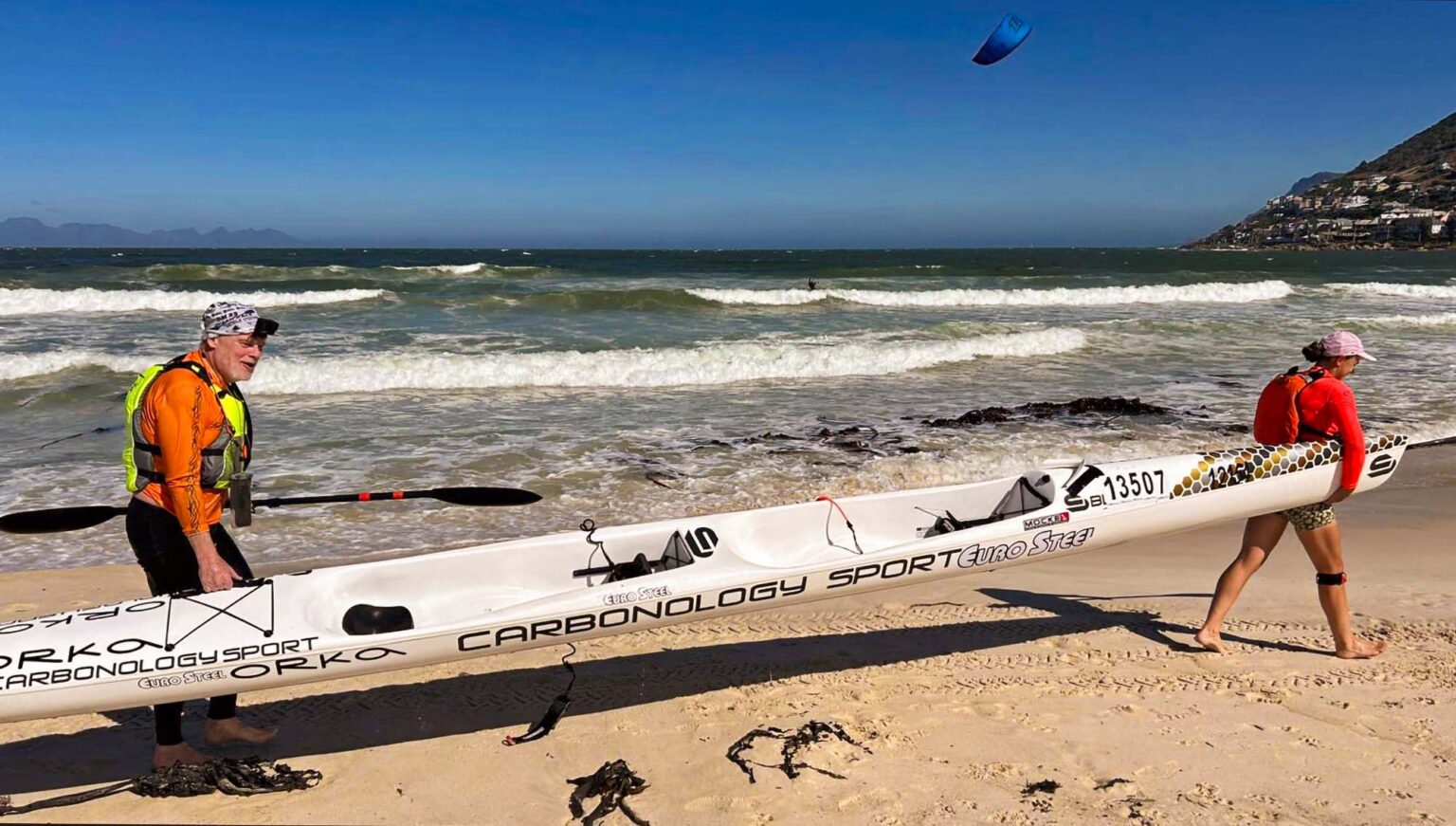 To roere bærer en toer-surfski på stranden