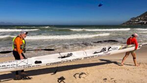 To roere bærer en toer-surfski på stranden
