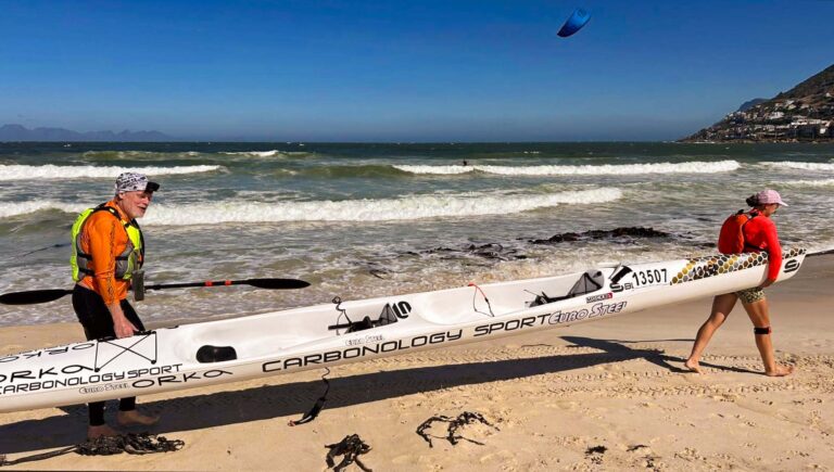 To roere bærer en toer-surfski på stranden